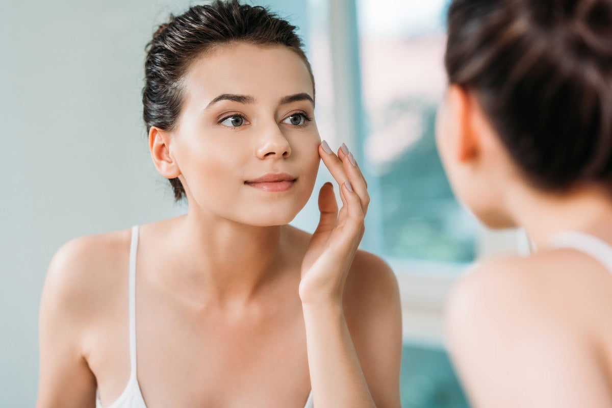 Young woman with beautiful skin applying Niacinamide cream on her face