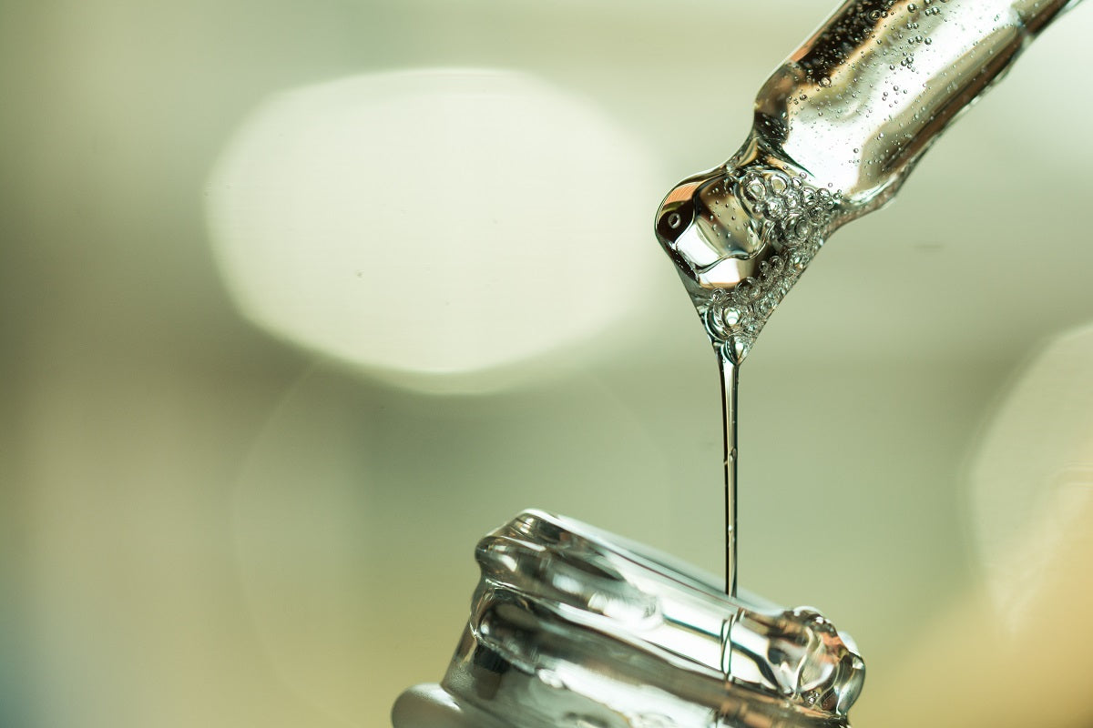Closeup of astream of Hyaluronic Acid dripping into little bottle